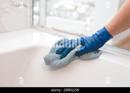 Die Hausfrau in den Handschuhen wäscht das Badezimmer Stockfoto