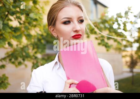 Nachdenkliche Schülerin mit einem Buch in der Hand denkt über das Studium nach Stockfoto