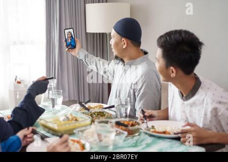 muslimische Familie Asian eid mubarak feiert Mittagessen zusammen zu Hause und einen Anruf an andere Familie Stockfoto