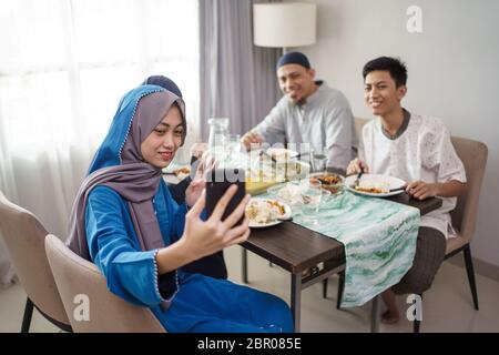 muslimische Familie Videoanrufe und Kontakt mit Freunden über Handy von zu Hause Stockfoto