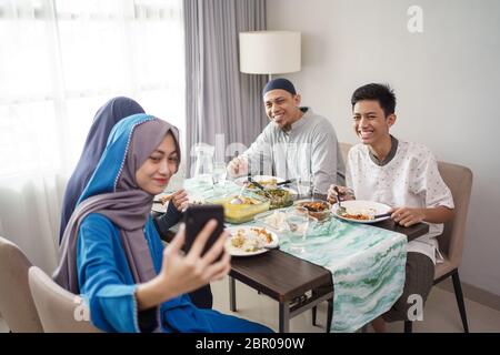 muslimische Familie Videoanrufe und Kontakt mit Freunden über Handy von zu Hause Stockfoto