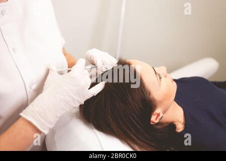 Mädchen hat Haarprobleme. Mesotherapie Verfahren. Arzt macht eine Injektion gegen Haarausfall. Stockfoto