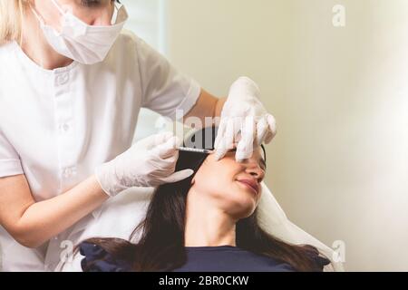 Die Kosmetikerin macht Anti-Aging-Injektionen für ihre Patientin. Frau kümmert sich um sich selbst und tut verjüngende Gesichts-Injektionen Stockfoto