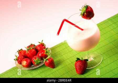 Erdbeer-Milchshake-Drink mit roten reifen Erdbeeren auf grünem und rosa Hintergrund. Stockfoto