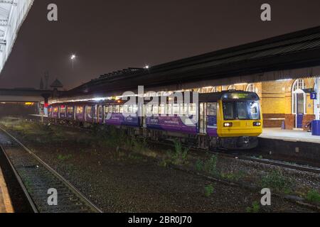 Der Pacer-Zug 142 der Nordbahn-Baureihe 142049 führt in einer dunklen Nacht im Regen den Sprinter 150 der Baureihe 150206 am Bahnhof Bolton an Stockfoto