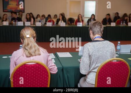 Menschen im Konferenzsaal. Rückansicht . Geschäftstreffen in einem Konferenzsaal. Rückansicht der Leute, die in der Konferenz holl am Tisch sitzen Stockfoto