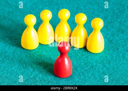 Concept Scene - ein roter Bauer vor mehreren gelben Bauern auf grünem Baize-Tisch Stockfoto