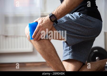 Nahaufnahme einer Person ist, die die Eisbeutel auf einem verletzten Knie in der Turnhalle Stockfoto