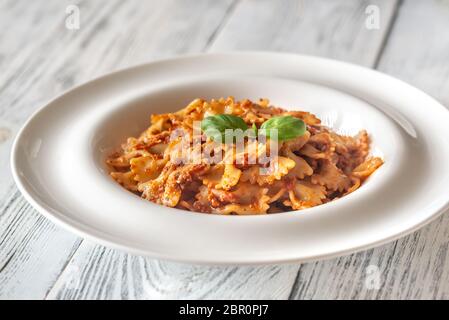 Teil von farfalle mit sonnengetrockneten Tomaten pesto auf die weiße Holztisch Stockfoto