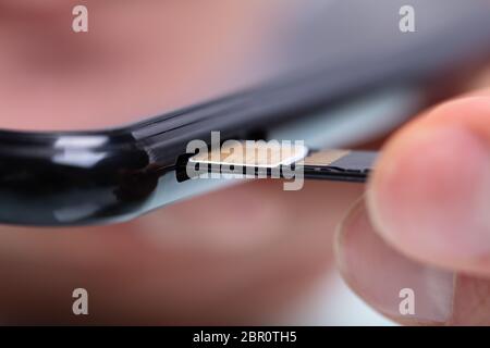 Nahaufnahme von einer Person Hand Einlegen der SIM-Karte im Handy Stockfoto