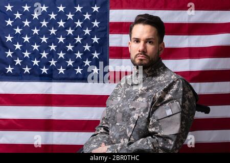 Seitenansicht der Veteran Sitzen im Rollstuhl Vor einer amerikanischen Flagge Stockfoto