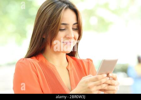 Smiley jugendlich in Orange verwendet Smart Phone zu Fuß auf der Straße Stockfoto