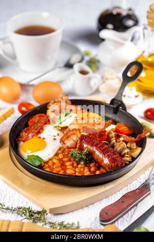 Englisches Frühstück mit Würstchen, gegrillte Tomaten, Pilze, Eier, Speck und Bohnen Stockfoto