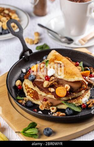 Stapel Pfannkuchen mit Beeren, Nüsse und Schokolade Soße zum Frühstück serviert. Stockfoto