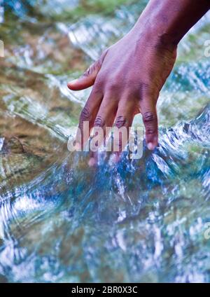 Wasser, Quelle des Lebens, und die Hand eines Jungen Stockfoto