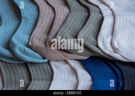 Socken aus feinem Jersey. Blick von oben. Viele Socken auf einem hölzernen Hintergrund. Socken in verschiedenen Farben. Strickmode. Stockfoto