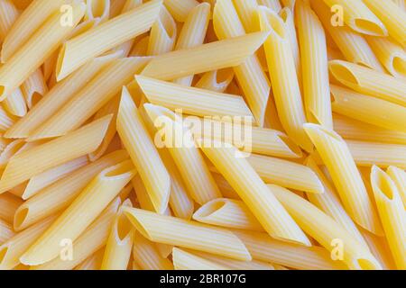 Hochwertige Penne Pasta Hintergrund. Rohe Bio-Penne. Traditionelle italienische Penne Pasta. Italienische Küche. Getrocknete Penne ohne Kochtkken. Draufsicht. Stockfoto