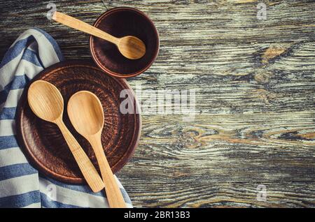 Kulinarische Hintergrund mit rustikalen Küchenutensilien: Keramische Platten, aus Holz oder Bambus Löffel und Handtuch auf vintage Holz- Hintergrund. Im rustikalen Stil. Home Küche Stockfoto