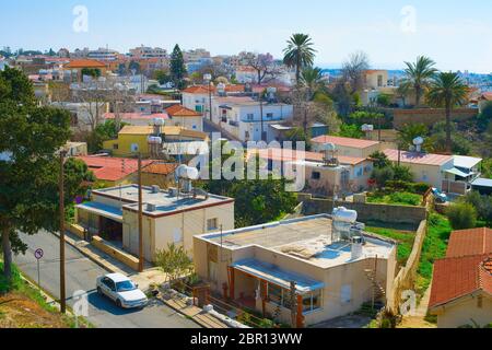 Antenne Skyline von Paphos Stadt im Sonnenlicht, Auto auf der Straße zwischen den Häusern der typischen Architektur, Palmen und grünen Bäumen, Zypern Stockfoto