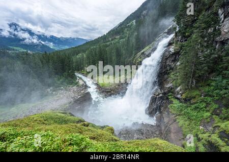 Idyllische Sicht auf die Krimmler Wasserfälle und den umliegenden Wald an einem wolkigen und nebligen Tag in Österreich bei Salzburg. Majestätischer Strom fließt am h Stockfoto