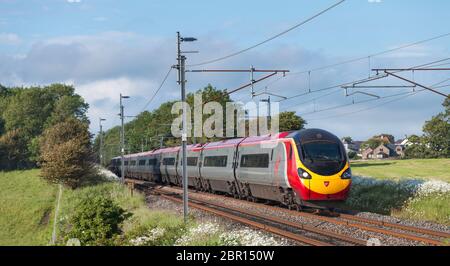 Virgin Trains Alstom Pendolino Zug auf der Westküste Hauptlinie vorbei an den grünen Feldern bei Bolton Le Sands, Lancashire Stockfoto