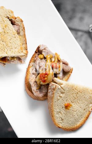 Berühmte traditionelle portugiesische bifana würzig mariniertes Schweinefleisch sandwich Snack mit Senf piri piri Sauce und Knoblauch in Lissabon Cafe Stockfoto