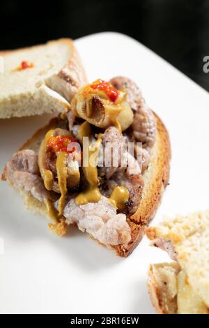 Berühmte traditionelle portugiesische bifana würzig mariniertes Schweinefleisch sandwich Snack mit Senf piri piri Sauce und Knoblauch in Lissabon Cafe Stockfoto