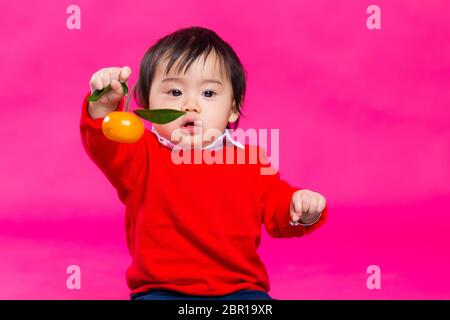 Asiatische Baby Junge hält eine Mandarine für Mond Neujahr Stockfoto