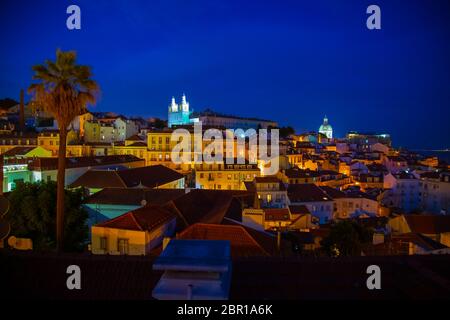 Nachtansicht des Alfama-Viertels und der Santo Estevao-Kirche vom Aussichtspunkt Miradouro das Portas do Sol in Lissabon, Portugal Stockfoto