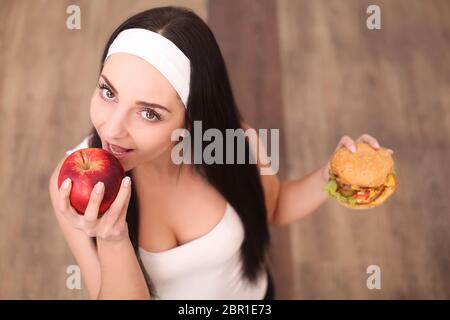 gesunde Frau riechen, Hamburger und Holding-Apfel Stockfoto