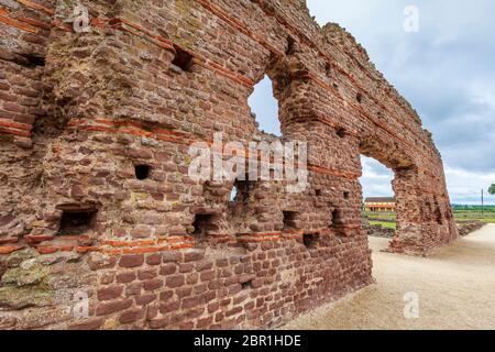 Die Überreste der Basilica Wand der Bäder in Wroxeter mit einer rekonstruierten römischen Villa durch den Bogen, Shropshire, England Stockfoto