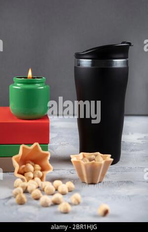 Genießen Sie das Lesen eines Buches mit einem Thermoskaffee begleitet von einer Kerze, die friedlich brennt. Stockfoto