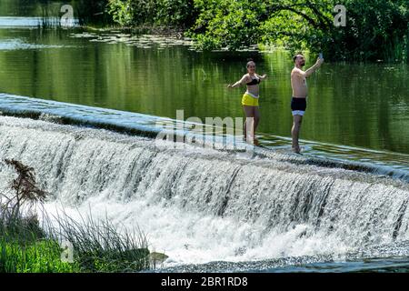 Die Menschen genießen das Wasser in Warleigh Weir am Fluss Avon in Somerset, während die Temperaturen über das Vereinigte Königreich steigen. Stockfoto