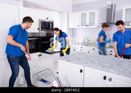 Gruppe von Jungen Hausmeister in Uniform Reinigung Küche zu Hause Stockfoto
