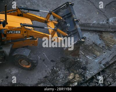 CHARKOW, UKRAINE - MAI 2020. Hydraulische Bagger Entfernen von Asphaltresten. Straßenumbau. Reparatur von Straßenbelag Stockfoto