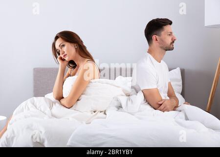 Seitenansicht des Verzweifelten Ehepaar Rücken an Rücken auf dem Bett Stockfoto