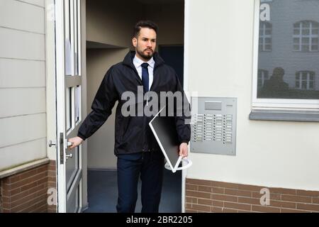 Junge männliche Techniker Öffnen der Tür beim Tragen Desktop in der Hand Stockfoto