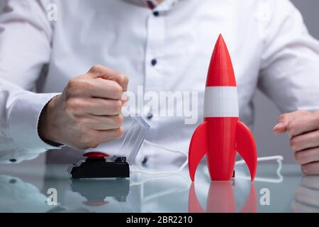 Der Geschäftsmann Hand mit Raketen durch Drücken der roten Taste Stockfoto