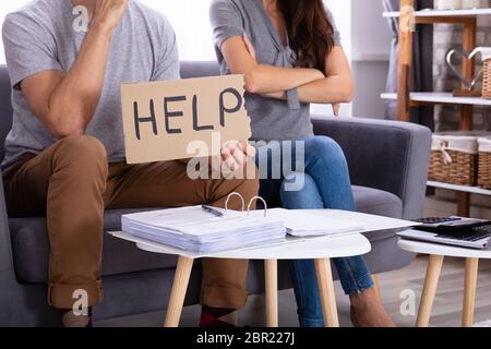 Junges Paar sitzt auf einem Sofa mit Hilfe Anmelden bei der Berechnung der Rechnung Stockfoto