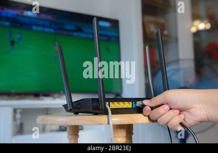 Women Hand verbindet das Internet-Kabel mit der Buchse des Routers Stockfoto