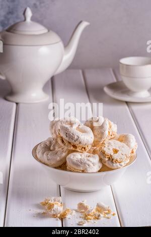 Süße Kuchen in einer Schüssel im Vordergrund und eine Teekanne und eine Teetasse auf verschwommenem Bokeh-Hintergrund. Stockfoto