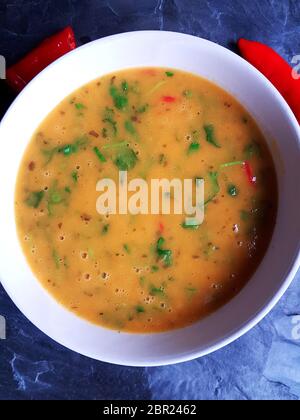 Rote Thai Hühnersuppe in einer weißen Schüssel mit roten Chilis auf Hintergrund Stockfoto