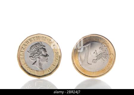 Eine Pfund-Münze mit dem Gesicht von Königin Elisabeth II. Vor einer 1-Euro-Münze, die am Rand und mit Spiegelung auf weißem Hintergrund thront Stockfoto