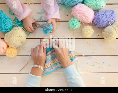 Mutter und Tochter Stricken Wollschal. Mama lehrt Kind zu stricken. Basteln und Hobby für Eltern und Kinder. Kleinkind Mädchen Kind mit Wolle Garn in einem Stockfoto