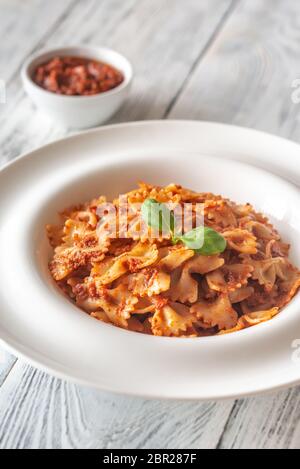 Teil von farfalle mit sonnengetrockneten Tomaten pesto auf die weiße Holztisch Stockfoto