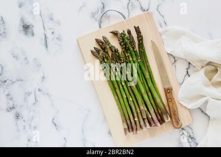 Grüner Spargel auf einem Marmortisch, flach mit einem Kopierraum Stockfoto