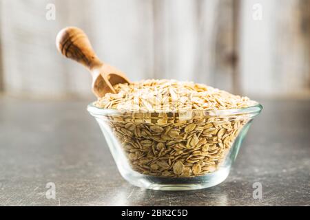 Trockene gewalzten Haferflocken in der Schüssel und hölzerne Schaufel. Stockfoto