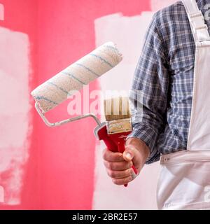 Kaukasische Haus Maler Arbeiter in weißen Overalls, Bürste und Walze für Malerei. Bauindustrie. Werkzeuge. Stockfoto