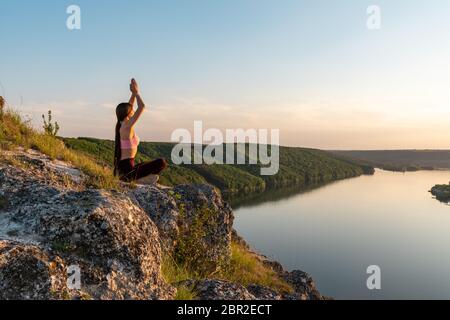 Junges Mädchen tun Yoga Fitness-Übung am Morgen Sonnenaufgang im Freien auf der Wiese schöne Berglandschaft Stockfoto