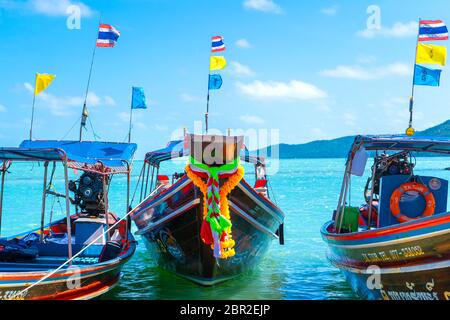 Thailändischer Logtail-Boot mit Dekorationen am Bug. Boot vor dem sandigen Ufer. Tropische Landschaft Stockfoto